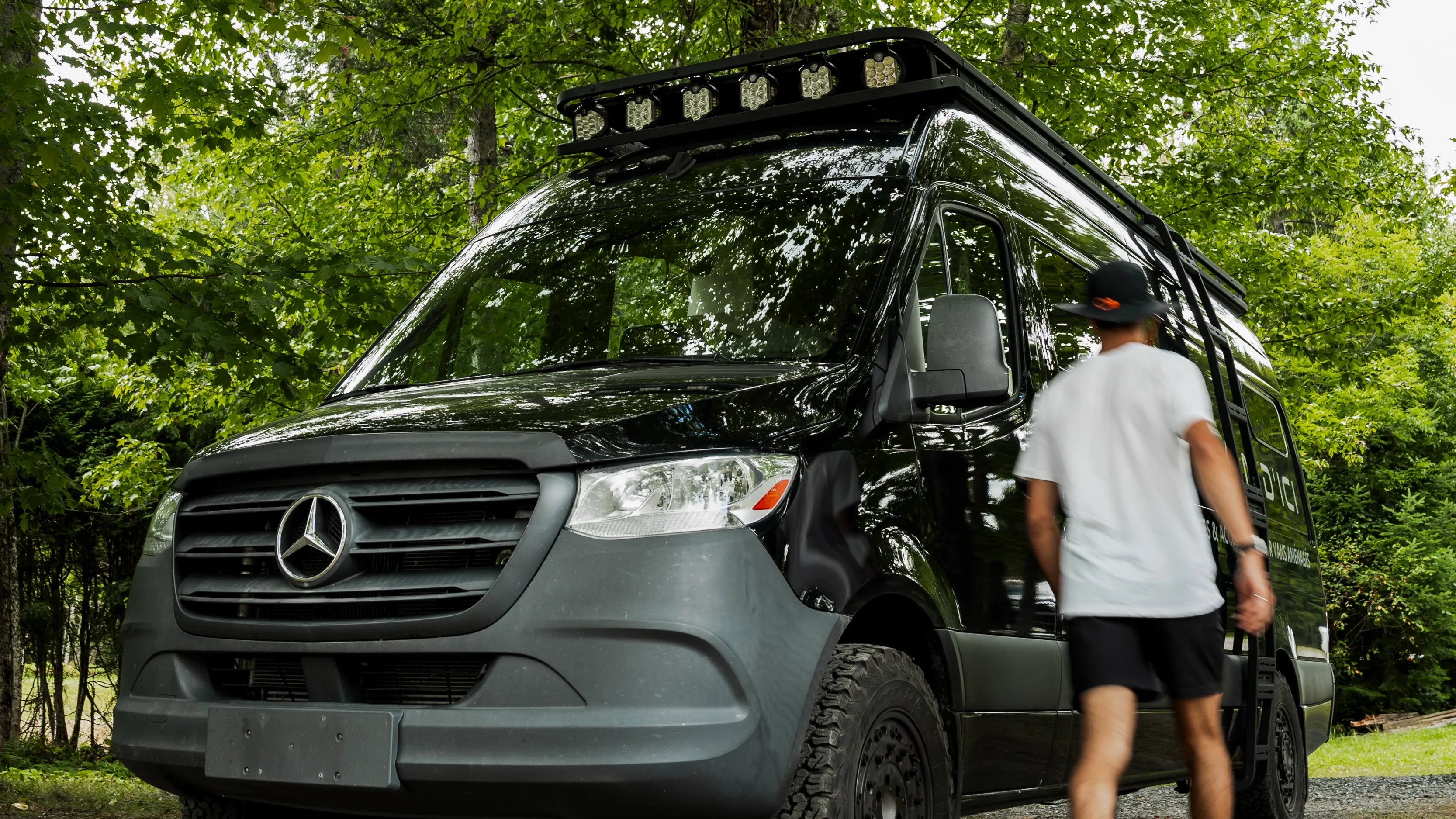 Person standing next to a Mercedes-Benz Class B van in a forested area